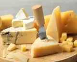 Deska serów: pleśniowy, camembert i twarde sery, w tym ser sałatkowy pokrojony w kostkę.
