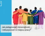 Grupa ludzi w kolorowych płaszczach obejmuje się, symbolizując inkluzywność i różnorodność w miejscu pracy.