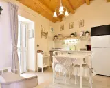Cuisine et coin repas dans un style shabby chic, avec des meubles blancs, des textiles doux et des poutres apparentes.