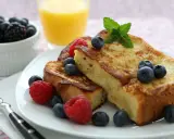 Deliciosa french toast receta, dorada y esponjosa, adornada con frambuesas, arándanos y menta. Un desayuno perfecto.