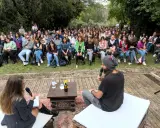 Un pubblico attento ascolta un dibattito all'aperto. Le parole fluiscono, profonde come il mare, leggere come il cielo.
