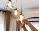 Man changing a lightbulb in a modern geometric pendant lamp, part of the simple home interiors.