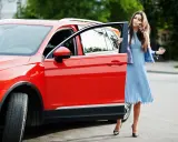 Mujer elegante sale de un monovolumen o SUV rojo brillante.