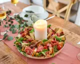 Festliche Platte mit Wurst, Käse, Oliven und Brot, ideal zum Antipasti selber machen. Eine Kerze in der Mitte sorgt für stimmungsvolles Licht.