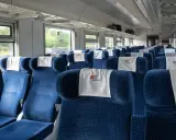 Puste niebieskie siedzenia w wagonie PKP Intercity z zagłówkami z logo.
