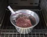Vildsvinskött i vakuumpåse i en skål med vatten, redo för sous vide. Kontrollerar innertemp för perfekt resultat.