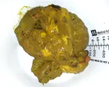 Feci oleose, di colore giallo-verdastro, con residui visibili e una consistenza untuosa. Accanto, una scala graduata.