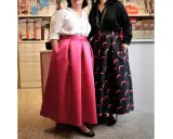Due donne mostrano diversi tipi di gonne: una rosa a pieghe e una nera con stampa a mezzelune rosa.