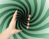 Main d'une personne tenant un smartphone avec un fond tourbillonnant vert et noir. Le téléphone affiche un motif de spirale hypnotique, comme un scroller def.