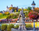 Statua sul ponte di Würzburg, con la fortezza in cima alla collina e i vigneti. Perfetto per un itinerario di 7 giorni sulla Romantische Straße.