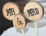 Drewniane krążki z napisami MR i MRS, symbolizujące Parę Młodą, ozdabiają tort.