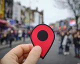 Symbol lokalizacji w dłoni, sugerujący zmianę miejsca prowadzenia działalności. W tle rozmyta ulica z ludźmi.
