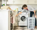 Hombre pone ropa en lavadora. Es importante recordar que hay que lavar la ropa interior nueva antes de usarla.