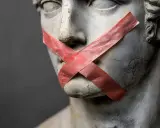 Busto di statua con nastro rosso a X sulla bocca, un esempio di antitesi tra arte e censura.