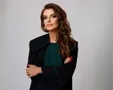Kobieta w todze prawniczej, z rękami skrzyżowanymi na piersi, na jasnym tle.