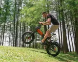 Un homme fait du vélo électrique sur une pente herbeuse, le pneu avant décollé du sol. Ce vélo électrique pour forte pente est idéal pour les terrains difficiles.