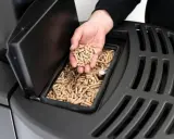 Mano sosteniendo **que es el pellet**, combustible para estufas, listo para ser añadido.