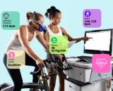 Frau auf Ergometer mit Maske, Trainer überwacht Werte wie VO2max (48 ml/kg/min) und anaeroben Schwellenwert (172 bpm).