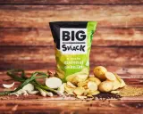 Reklamowa fotografia paczki chipsów "Big Snack" o smaku zielonej cebulki, z ziemniakami i cebulką w tle.