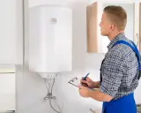 Técnico revisa un termo eléctrico que gotea, anotando en su portapapeles.
