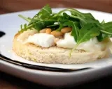 En bit rostat bröd med smält **chevre chaud**, pinjenötter och ruccola. En läcker förrätt.