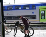 Ciclista con bici da gravel alla stazione, pronto per il viaggio da Rimini a Bellaria. Il treno Trenitalia è sullo sfondo.