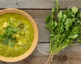Soupe crémeuse aux pommes de terre et au cresson de para frais, garnie de feuilles vertes.