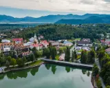Malownicze miasteczko w Chorwacji, otoczone zielonymi wzgórzami i górami. Jezioro odbija kolorowe dachy domów.