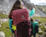 Dwie osoby w górach, jedna z plecakiem Deuter, wskazująca drogę.
