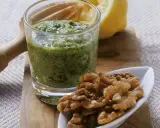 Frisches Petersilienpesto im Glas, daneben Walnüsse und eine Zitronenhälfte. Perfekt für Petersilie Rezepte.