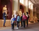 Un grupo de niños disfruta de las exposiciones en un museo de Madrid, aprendiendo sobre arte e historia con su guía.