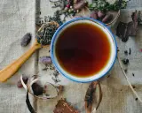 Une tasse de thé ambré, une cuillère de feuilles de thé, des fèves de cacao et des épices. Une invitation à découvrir les rooibos bienfaits.