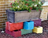 Un bac à fleurs sur des blocs de béton colorés, une idée de **diy jardin** pour rehausser vos plantes.