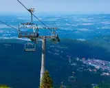 Karpacz i Szklarska Poręba z lotu ptaka. Kolejka linowa wznosi się nad zielonymi lasami i zabudowaniami.