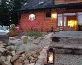 Przytulna bacówka na zadzielu wita gości. Drewniany dom, kamienny murek i kwitnące kwiaty tworzą sielski klimat.