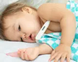 Małe dziecko z gorączką, termometr pod pachą. Trwa 3 dniówka u dziecka, które potrzebuje odpoczynku.