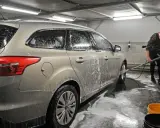 Mężczyzna myje samochód na myjni bezdotykowej. Poznaj myjnia bezdotykowa triki, by uzyskać lśniący efekt.