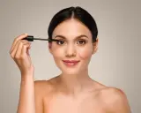 Mujer aplicando máscara de pestañas, un paso esencial para aprender como aplicar sombras de ojos principiantes y realzar la mirada.
