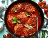 Un saporito pollo in umido, cotto lentamente in una ricca salsa di pomodoro, guarnito con basilico fresco e alloro.