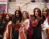 Six young women proudly showcase traditional Palestinian attire, highlighting the vibrant artistry of Palestinian designers.