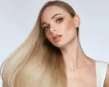 Blonde Frau mit glänzendem Haar, das durch Proteine gestärkt wurde.