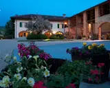 Un casale illuminato al crepuscolo, con fiori colorati in primo piano. Ideale per un weekend degustazione vini Piemonte.