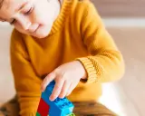 Niño concentrado jugando con bloques de construcción. Un ejemplo de cómo el juego puede ayudar a superar un retraso madurativo y TDAH.