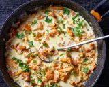 Pfifferlinge in cremiger Rahmsauce, garniert mit frischer Petersilie, in einer Pfanne. Ein Löffel ragt aus der köstlichen Speise.