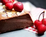 Une délicieuse marquise au chocolat, garnie de cerises fraîches et d'amandes effilées, prête à être dégustée.
