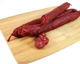 Trzy kawałki pikantnego chorizo na desce. Zastanawiasz się chorizo co to? To aromatyczna, suszona kiełbasa.