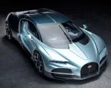 Ein neuer Bugatti in schimmerndem Blau steht auf dunklem Untergrund. Sein Design ist aerodynamisch und luxuriös.