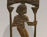 Sculpture en bois d'un musicien égyptien jouant d'un instrument ancien, ornée de motifs floraux.