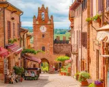 Un vicolo pittoresco a Gradara e dintorni, con case in mattoni, negozietti e un'antica torre dell'orologio.
