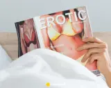 Mężczyzna w łóżku czyta magazyn "Erotic", przygotowując się do masturbacji przed seksem.